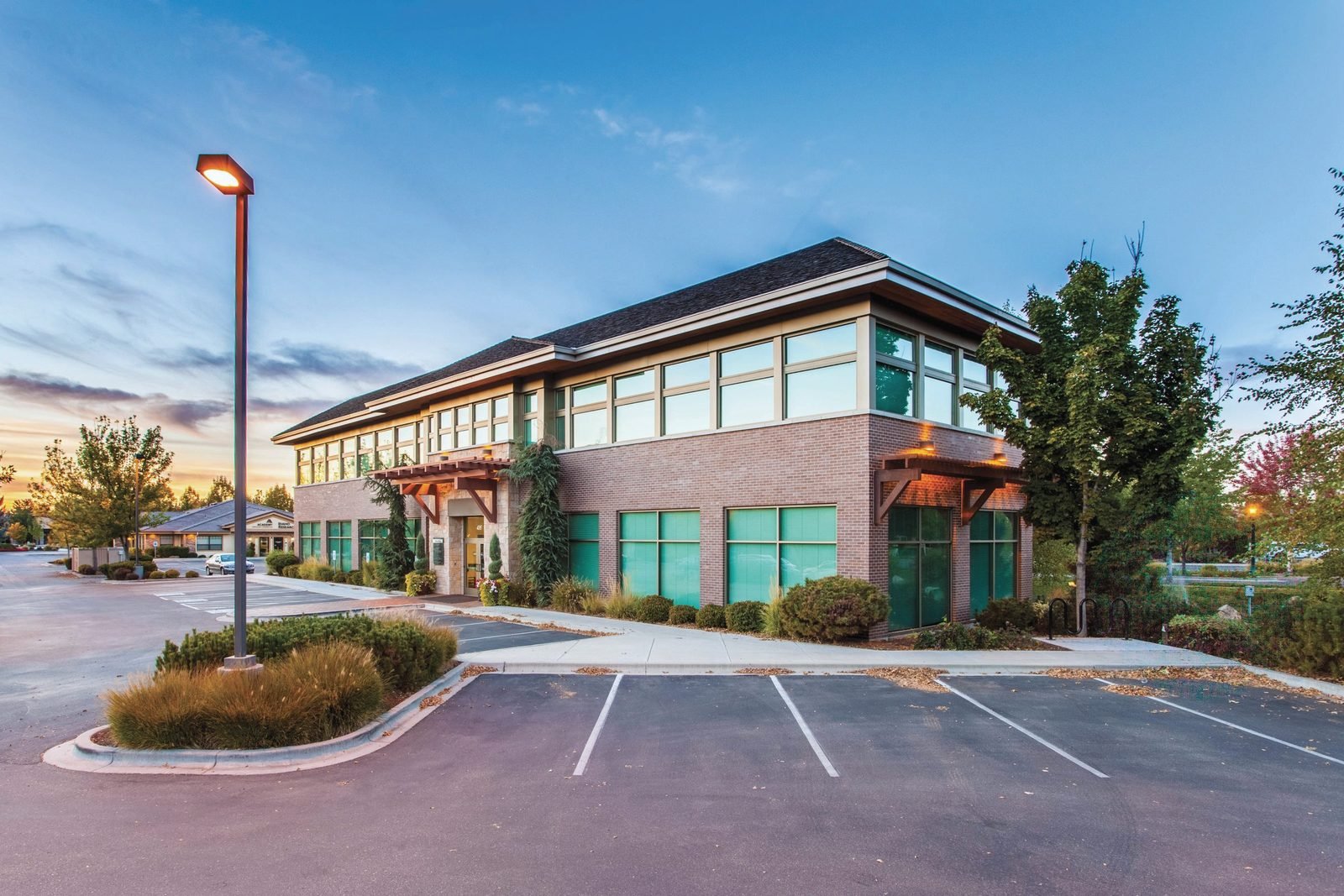 A low brick professional building with parking at dusk