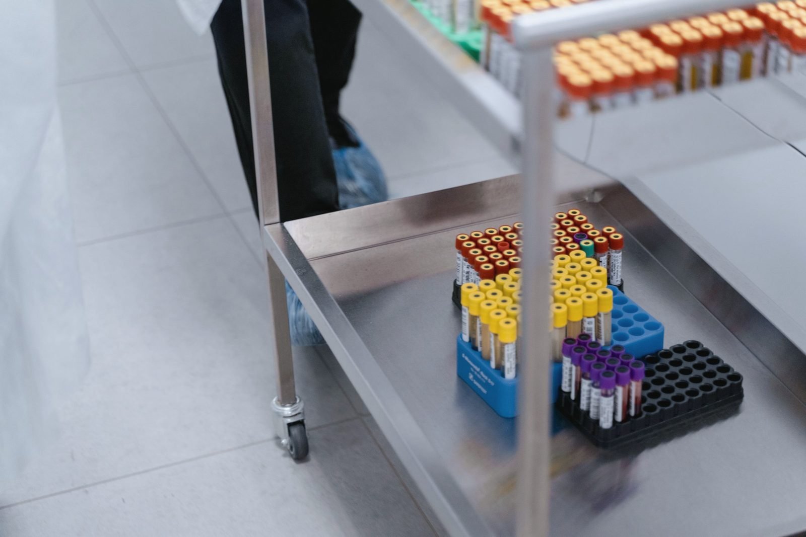 A stainless steel cart holding racks of labelled sample tubes