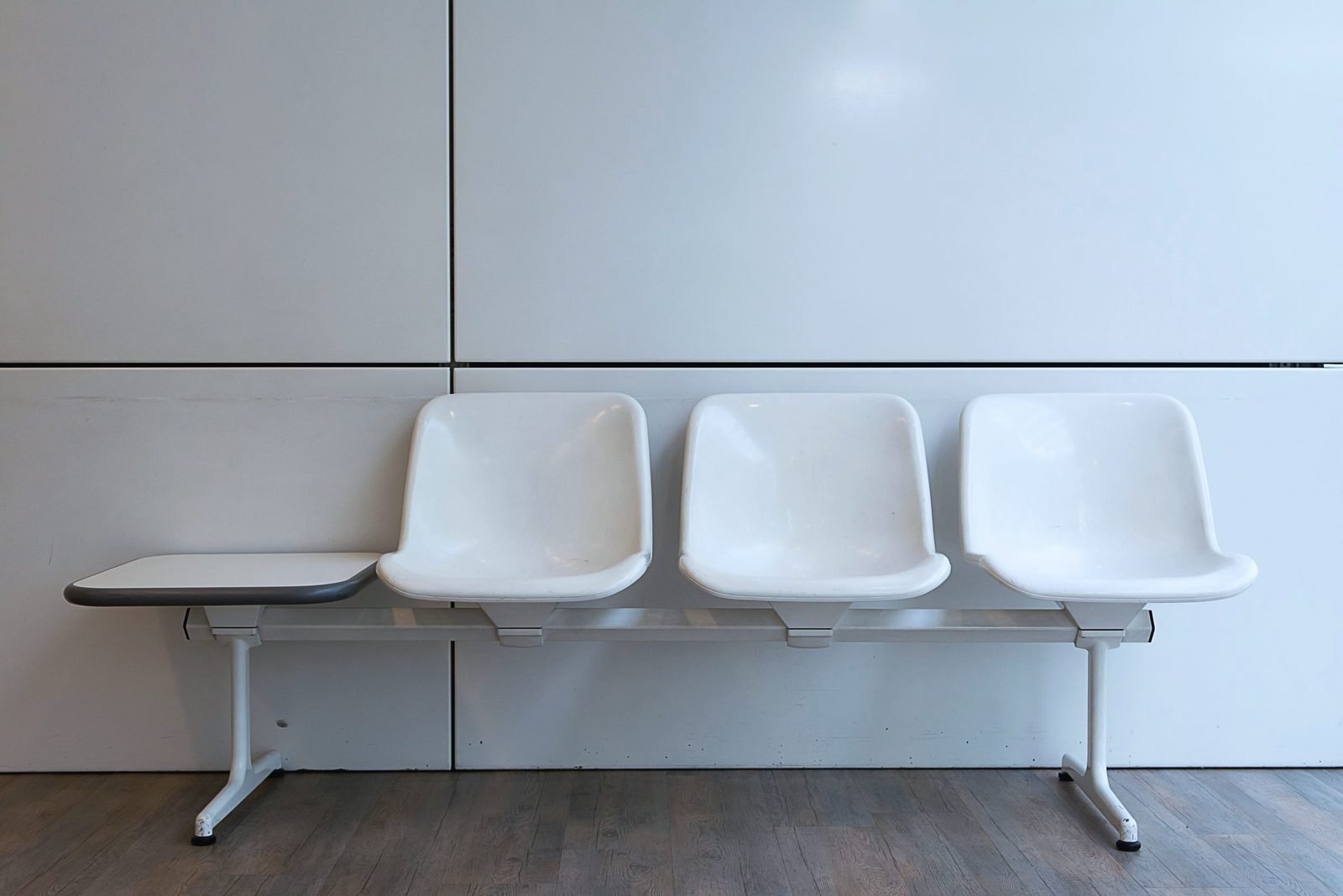 A row of white waiting room chairs against a pale wall